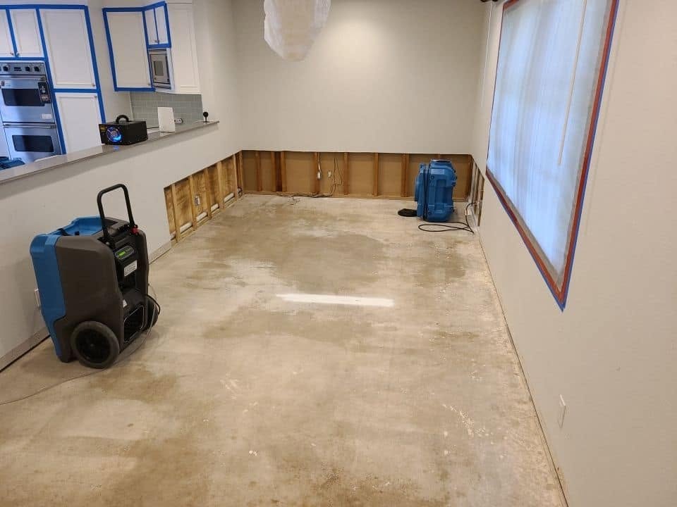 Drying equipment and dehumidifiers running in water-damaged room with removed drywall
