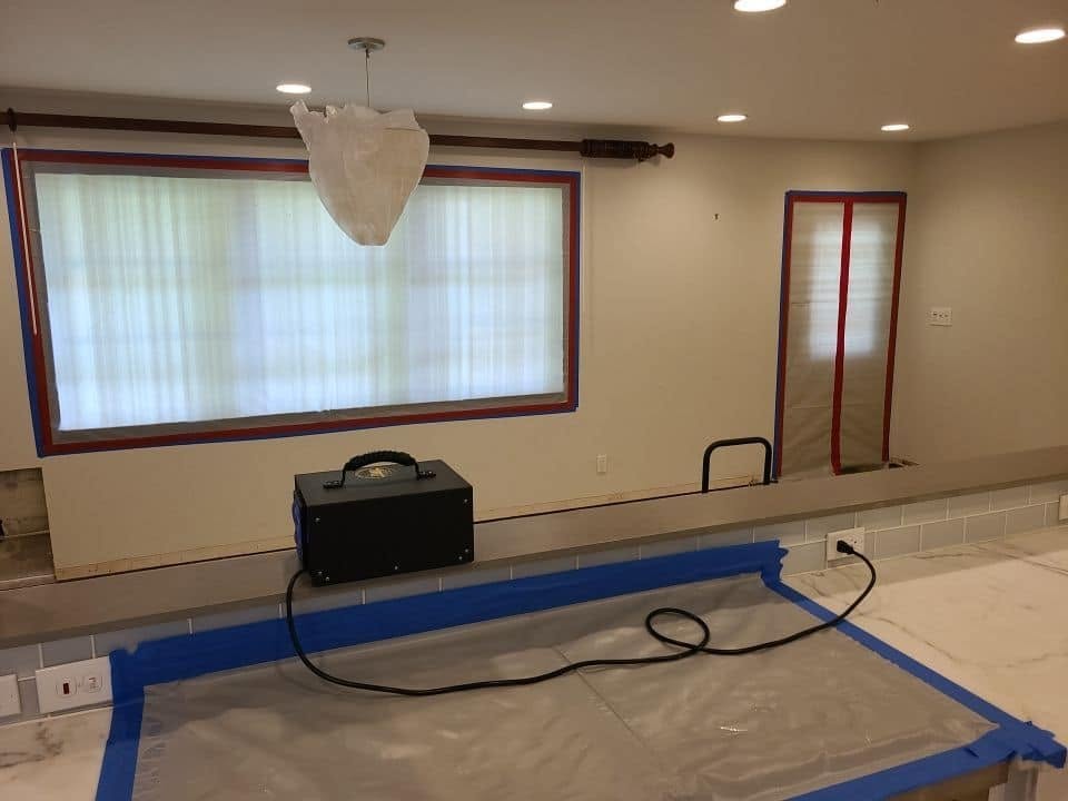 Mold remediation technician in full PPE suit treating wall surface