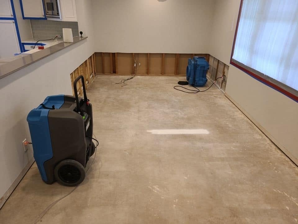 Wide view of water damage restoration with multiple drying units in open room