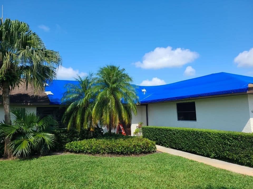 Florida home with blue tarp covering roof after storm water damage