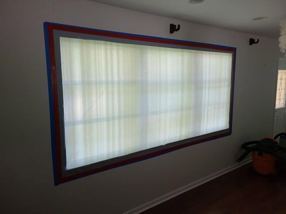Window sealed with blue and red tape containment barrier during water damage restoration
