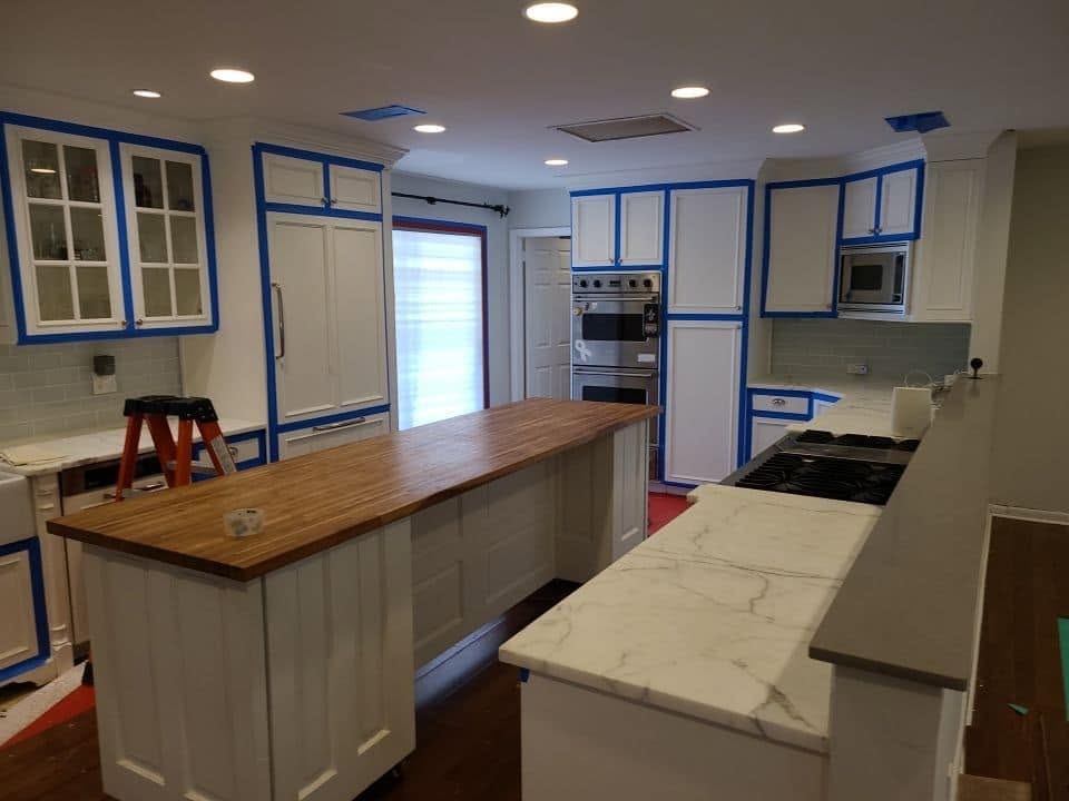 Restored kitchen with new countertops and blue painter's tape on cabinets during post-water damage rebuild