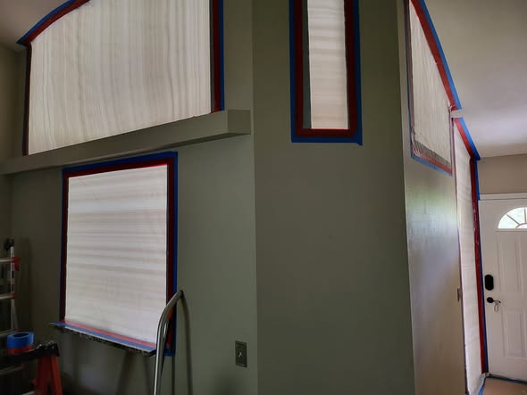 Mold remediation technician in full PPE wiping sliding glass door in condo unit during mold cleanup