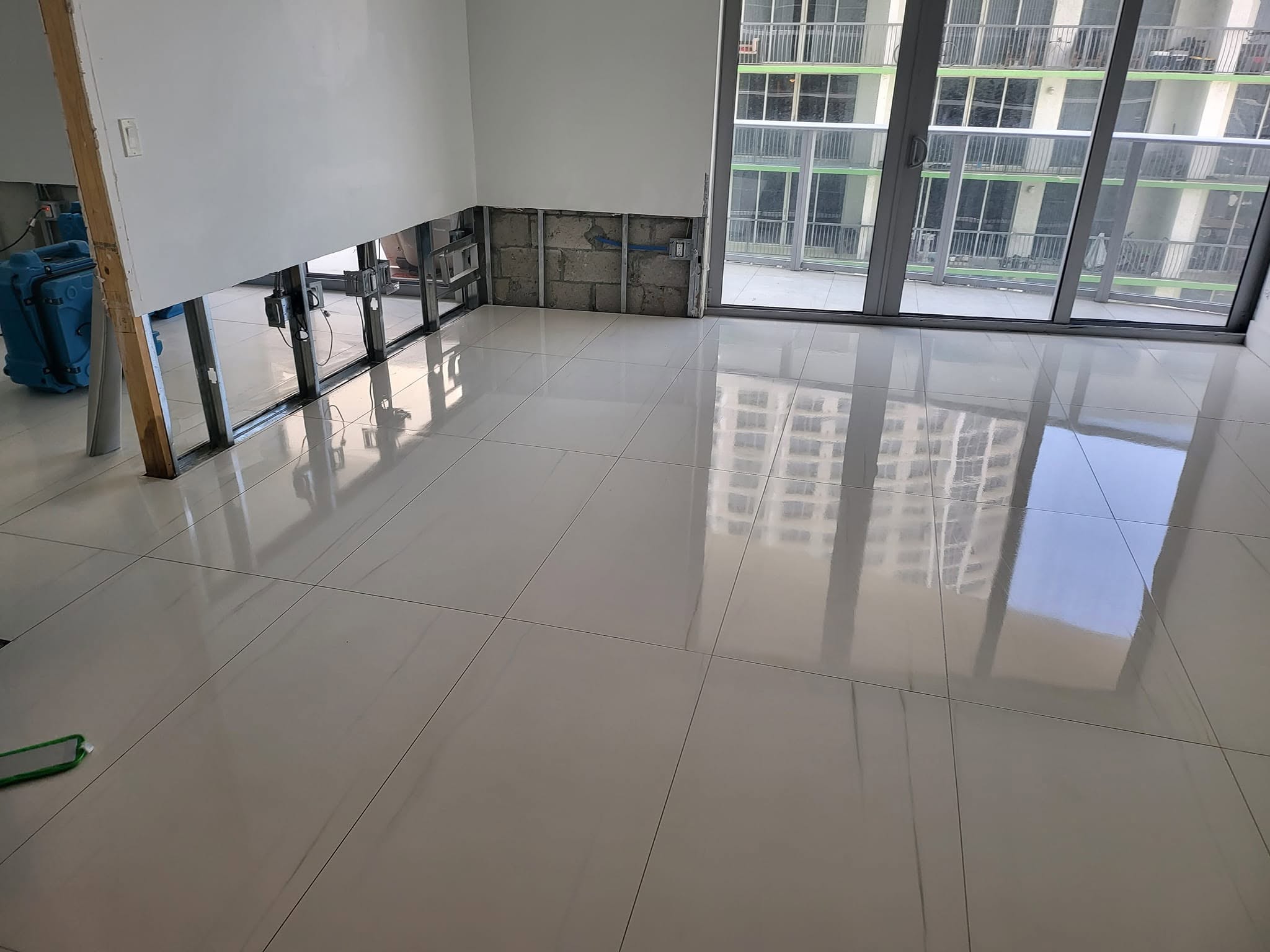 Condo unit with blue air mover running and removed drywall section during water damage mitigation