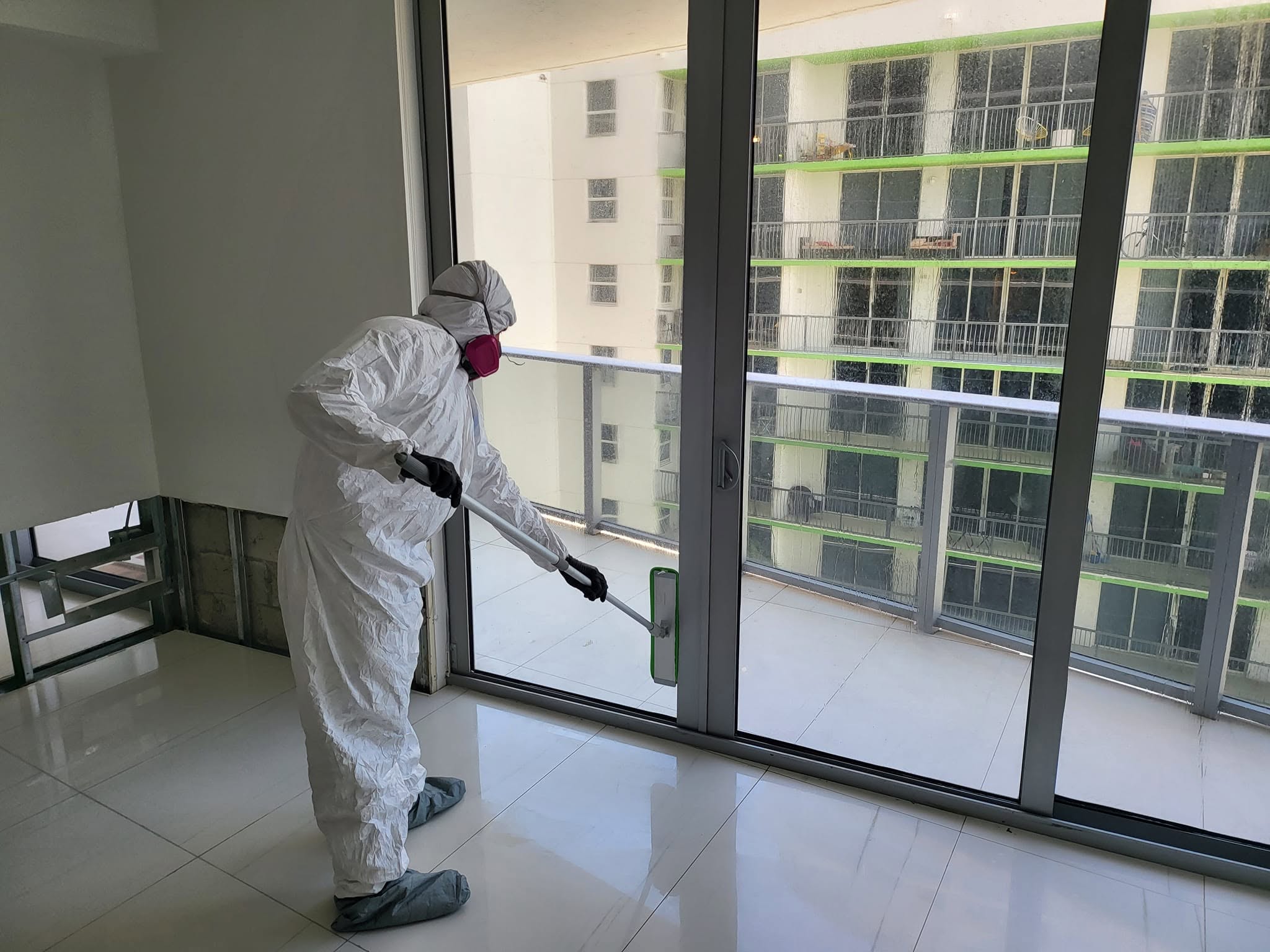 Large living room windows sealed with blue and red tape containment barriers during mold remediation