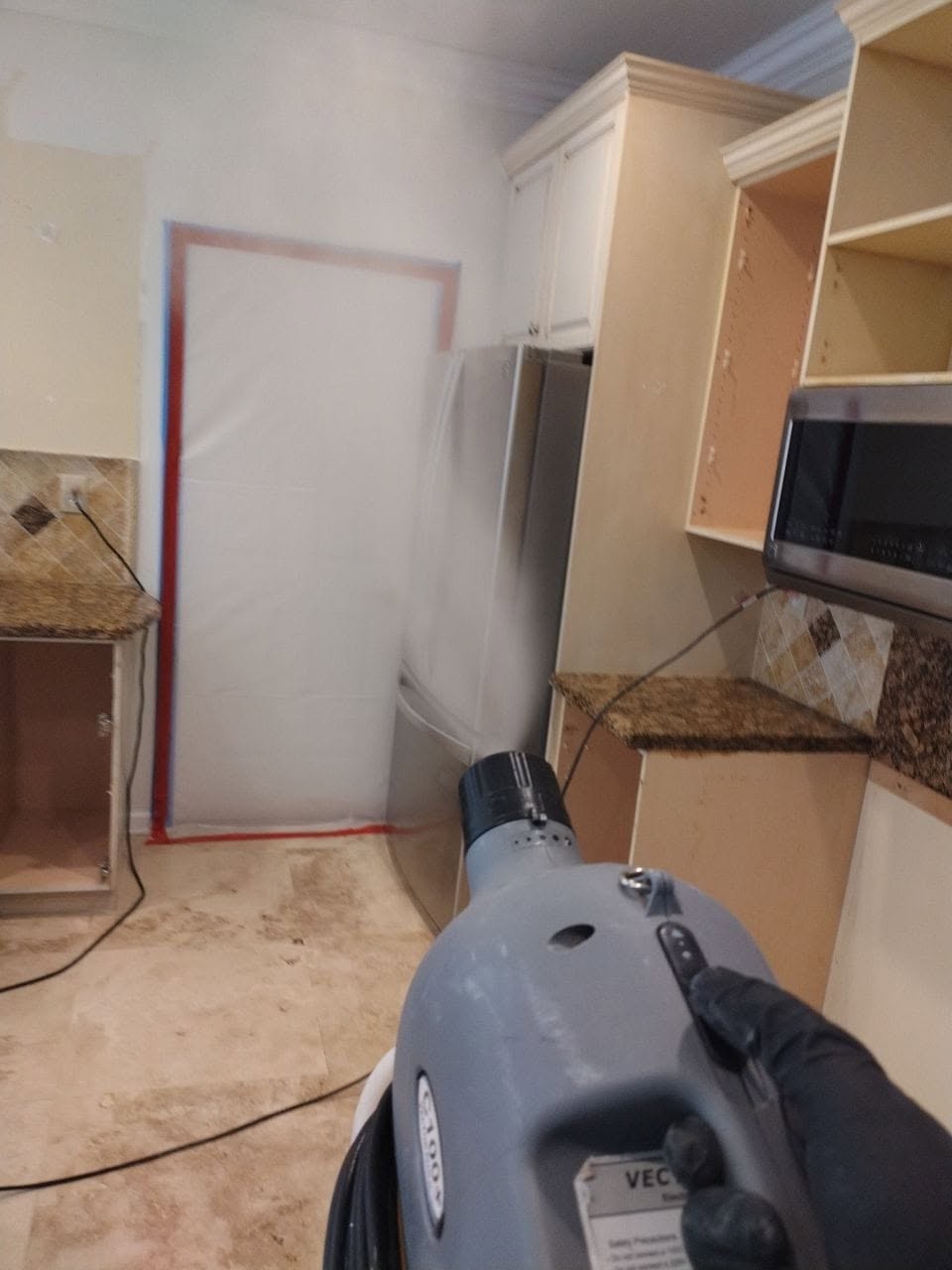 Full plastic containment wall with red poles and red tape sealing off mold remediation work area