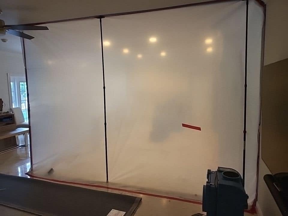 Fogging machine dispensing antimicrobial treatment in kitchen with blue and red tape containment barrier